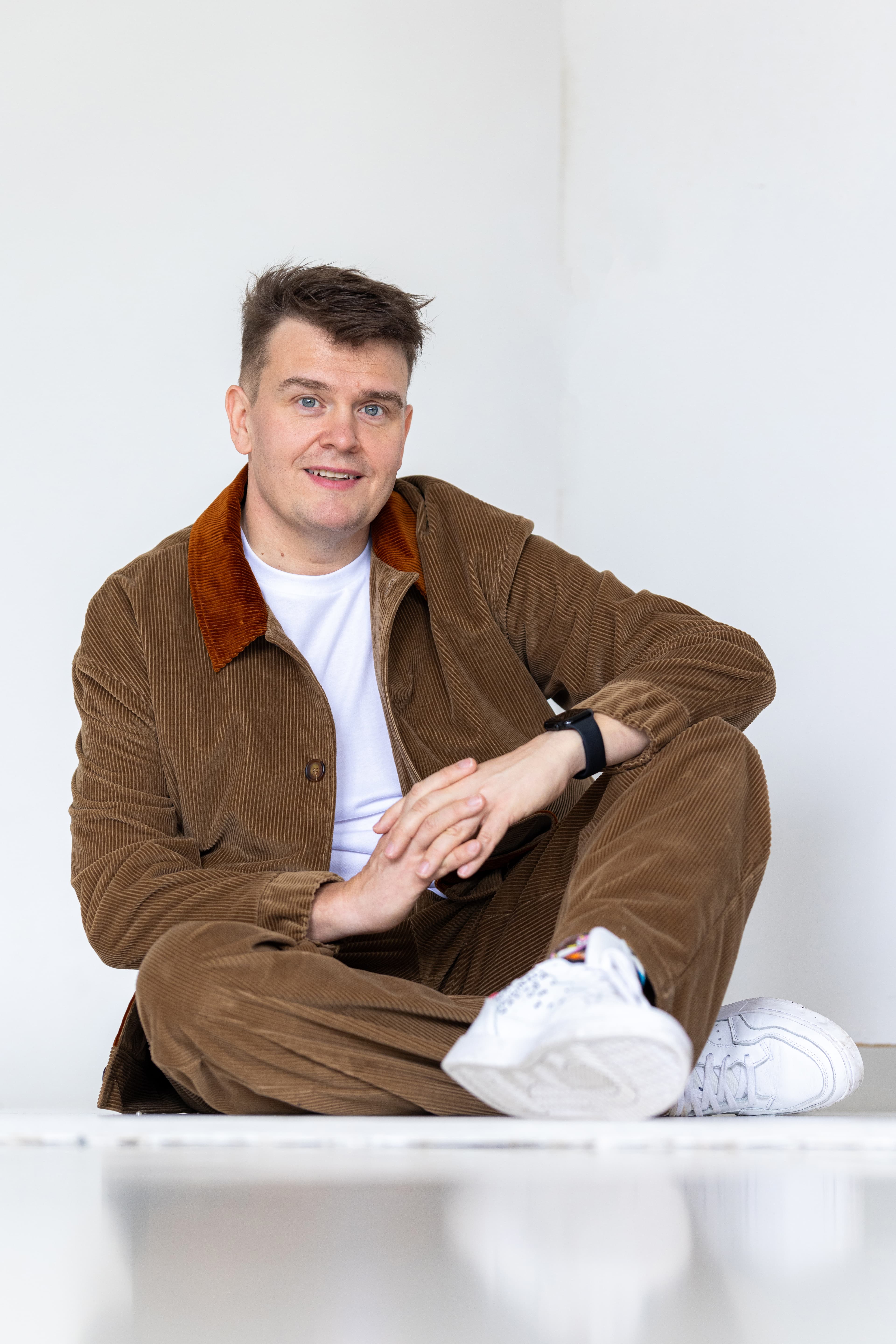 JP Pirinen istumassa, kädet ristissä, rentona