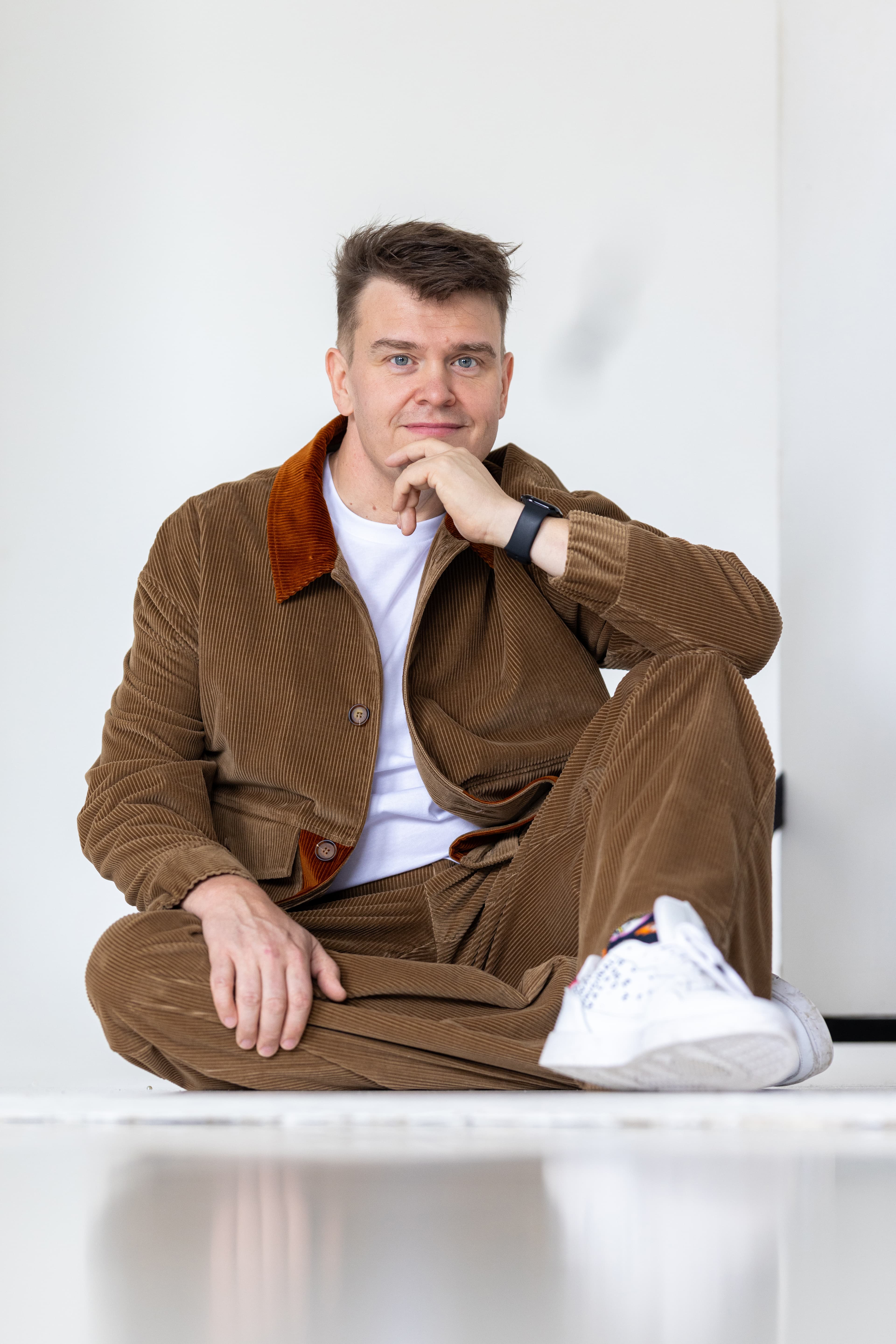 JP Pirinen istumassa, käsi leuan lähellä, mietteliäänä